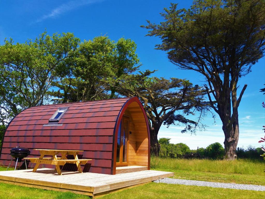 a red roofed cabin with a picnic table on a deck at Robin- Ensuite Glamping Pod in Truro