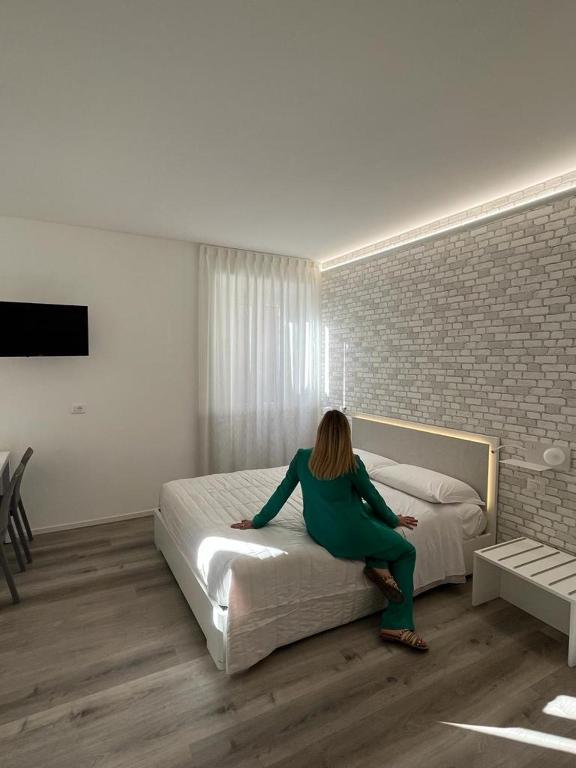 uma mulher sentada numa cama num quarto em Rosso Conero - Le Grotte Rooms & Apartments em Camerano