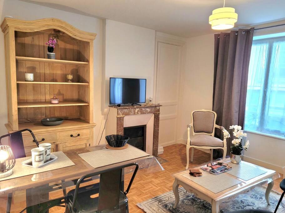uma sala de estar com uma mesa e uma lareira em Le Bohème, appartement de charme hyper centre em Granville
