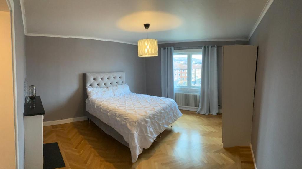 1 dormitorio con cama blanca y ventana en Iris en Huskvarna