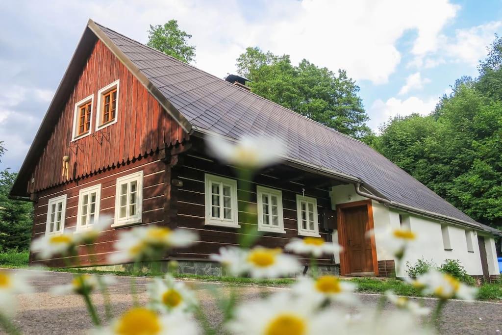 een rood-wit huis met bloemen ervoor bij Javorník u Tichých in Rudník