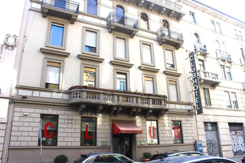 a large white building with balconies on a street at Club Hotel in Milan