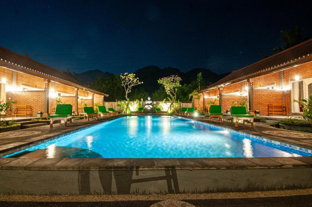 una piscina por la noche con sillas y luces en Kubuku Eco Dive Lodge and Yoga, en Pemuteran