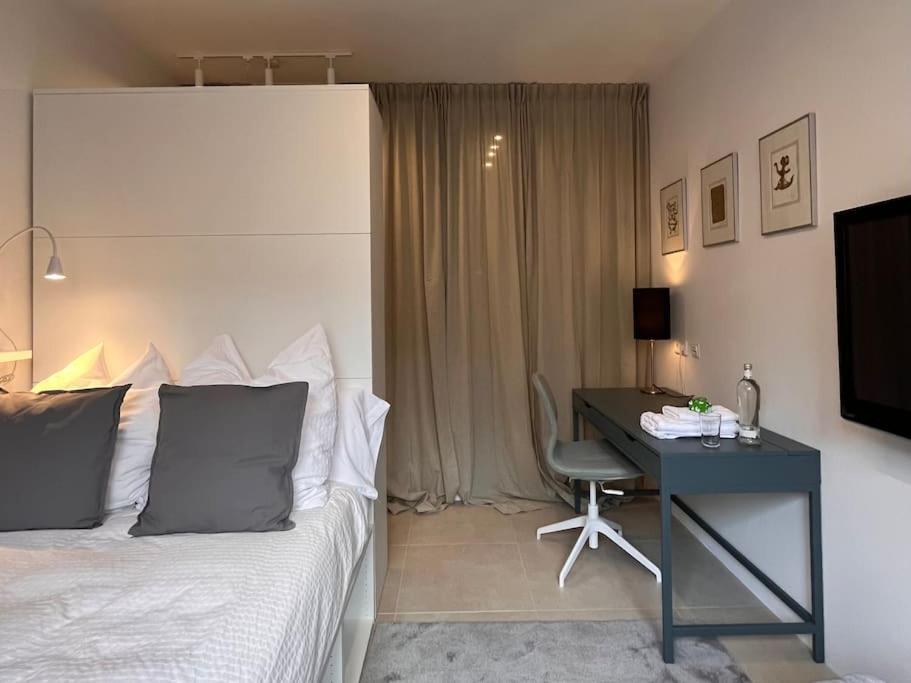 um quarto com uma cama e uma secretária com um computador em Quiet and sunny studio in Ddorf absolut city center em Dusseldorf