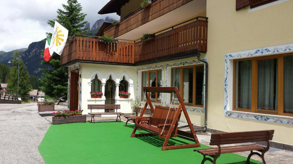 una casa con un césped verde con dos sillas. en IHR Hotel Villa Emma, en Canazei