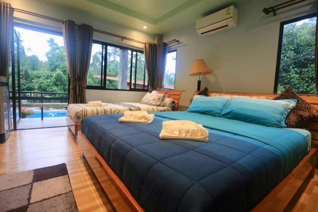 een slaapkamer met een groot blauw bed en handdoeken bij ปลายน้ำรีสอร์ท พรหมคีรี นครศรี ฯ Plainam Resort in Ban Khaek