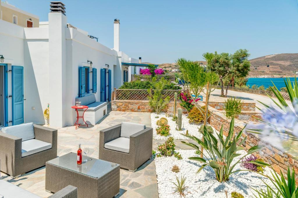 un patio con sillas y mesas y vistas al océano en Villa Maria Fabrika Syros, en Vári