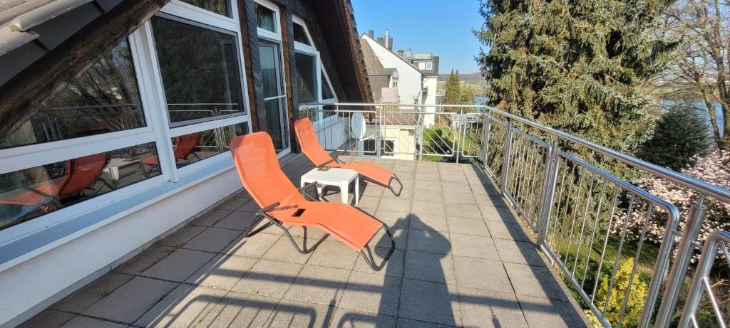 Duas cadeiras cor-de-laranja sentadas numa varanda em Vierzimmerwohnung am Harkortsee em Wetter