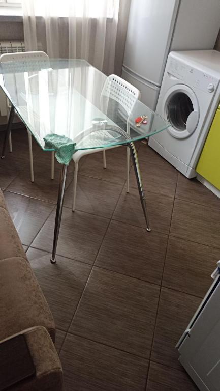 uma mesa de vidro e uma cadeira ao lado de uma máquina de lavar roupa em New vip 287 em Tbilisi