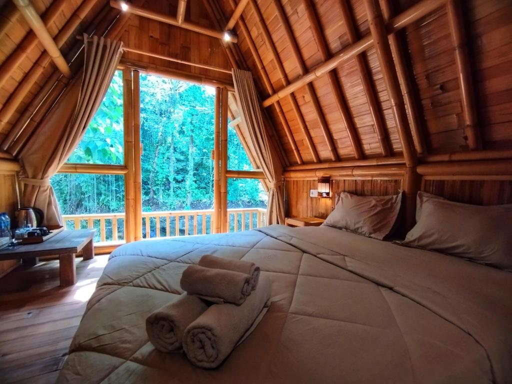 a large bed in a room with a large window at Aksha Riverside Ubud in Tampaksiring