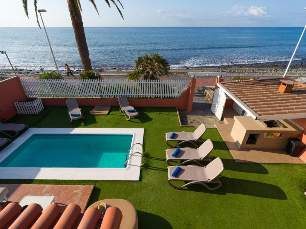 una piscina con sillas y el océano en el fondo en El Veril by CanariasGetaway, en San Agustín