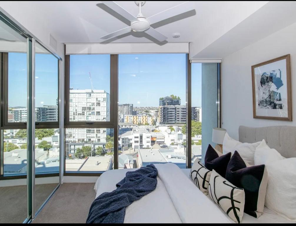 a bedroom with a ceiling fan and a large window at Axle x Apartment in Brisbane