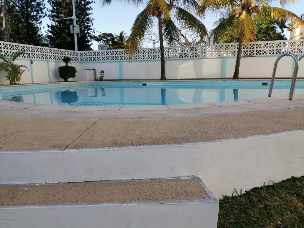 a swimming pool with palm trees next to a building at Les Filaos De Pereybere in Pereybere