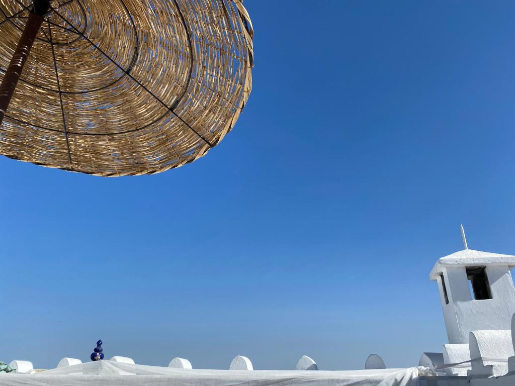 a person standing under a straw umbrella next to a building at Dar Nour in Tangier