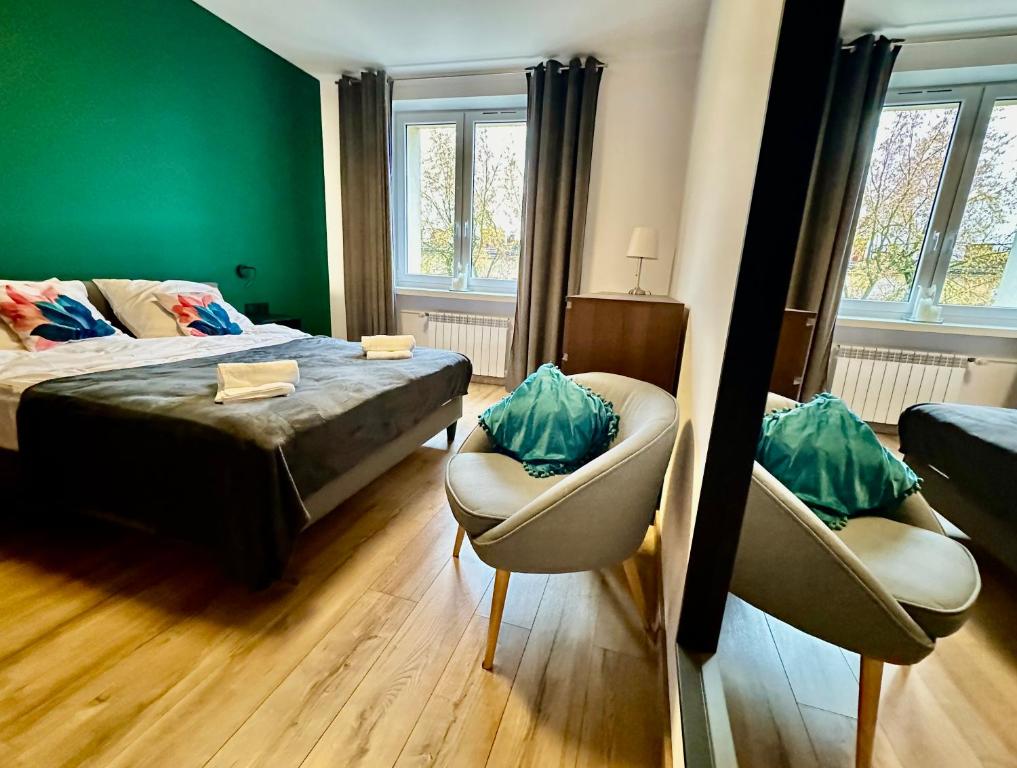 um quarto com uma cama, 2 cadeiras e um sofá em Jazz Apartament Częstochowa Centrum 2-bedroom em Czestochowa