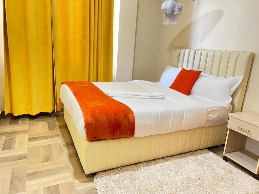 um quarto com uma cama com almofadas laranja e branca em Lake View Plaza Apartments Nakuru Town em Nakuru