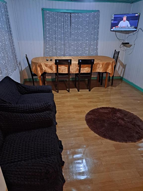 een woonkamer met een tafel en stoelen en een televisie bij Cabaña huenuco rural castro in Castro