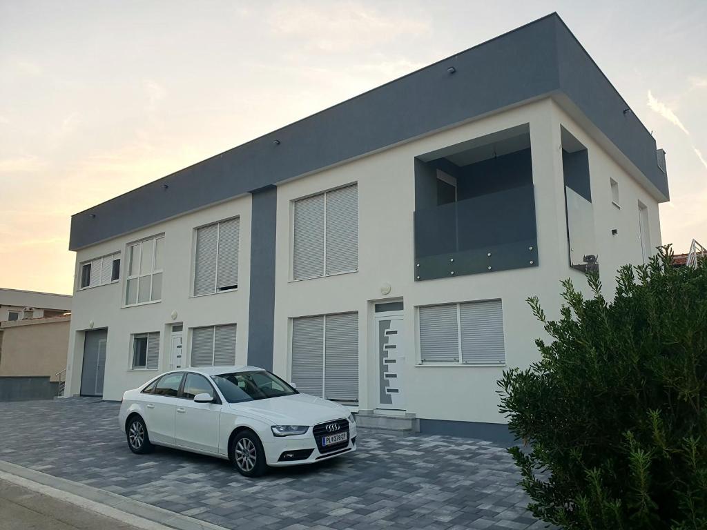 a white car parked in front of a house at Apartmani Stipe in Vir
