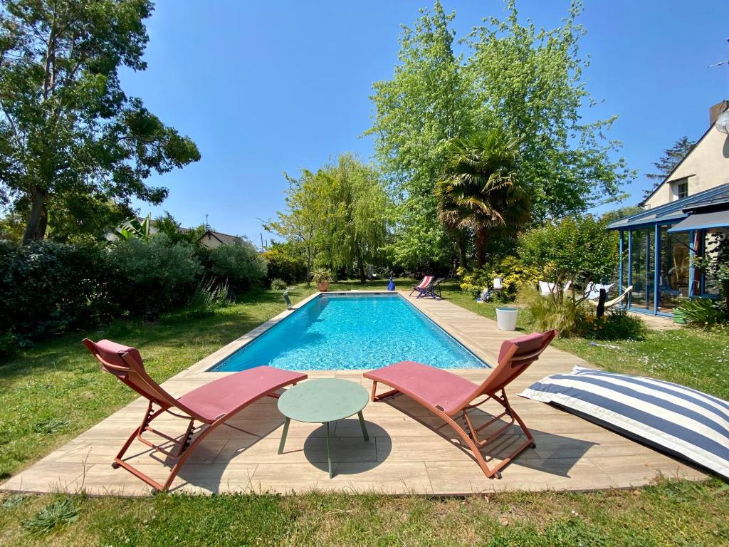 una piscina con 2 sillas y una mesa al lado en Casa Sorriso, en La Daguenière