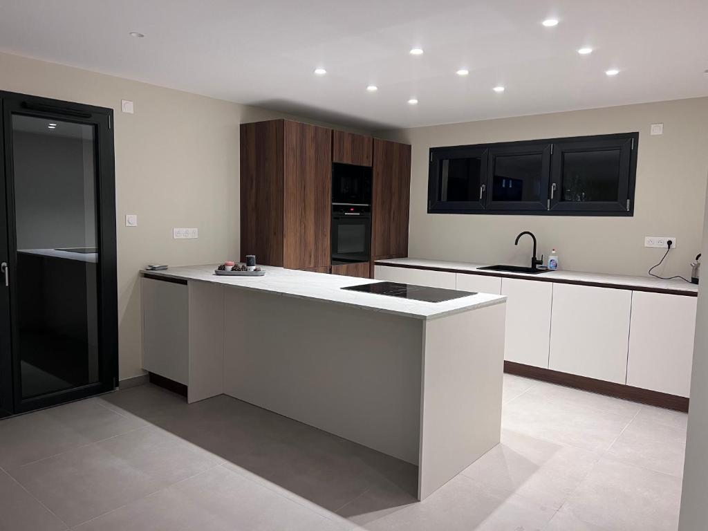 une cuisine avec un îlot blanc au milieu dans l'établissement Maison harmonie, à Colmar