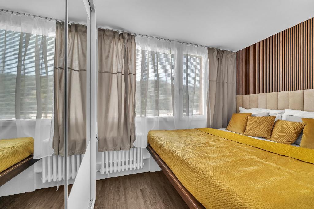 - une chambre dotée d'un lit avec des draps jaunes et des fenêtres dans l'établissement Apartmán Malina, à Svoboda nad Úpou