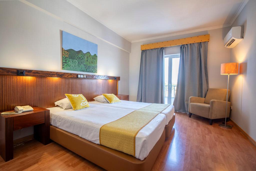 a hotel room with a large bed and a chair at Hotel Onix in Viseu