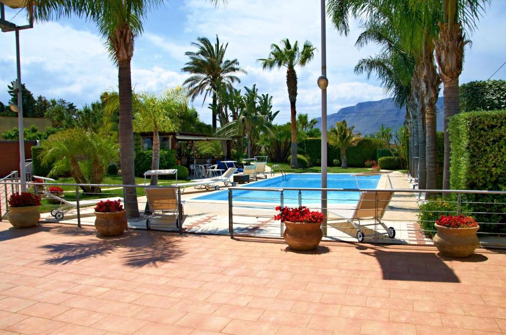 a swimming pool with two chairs and palm trees at Villa Palme in Alcamo Marina