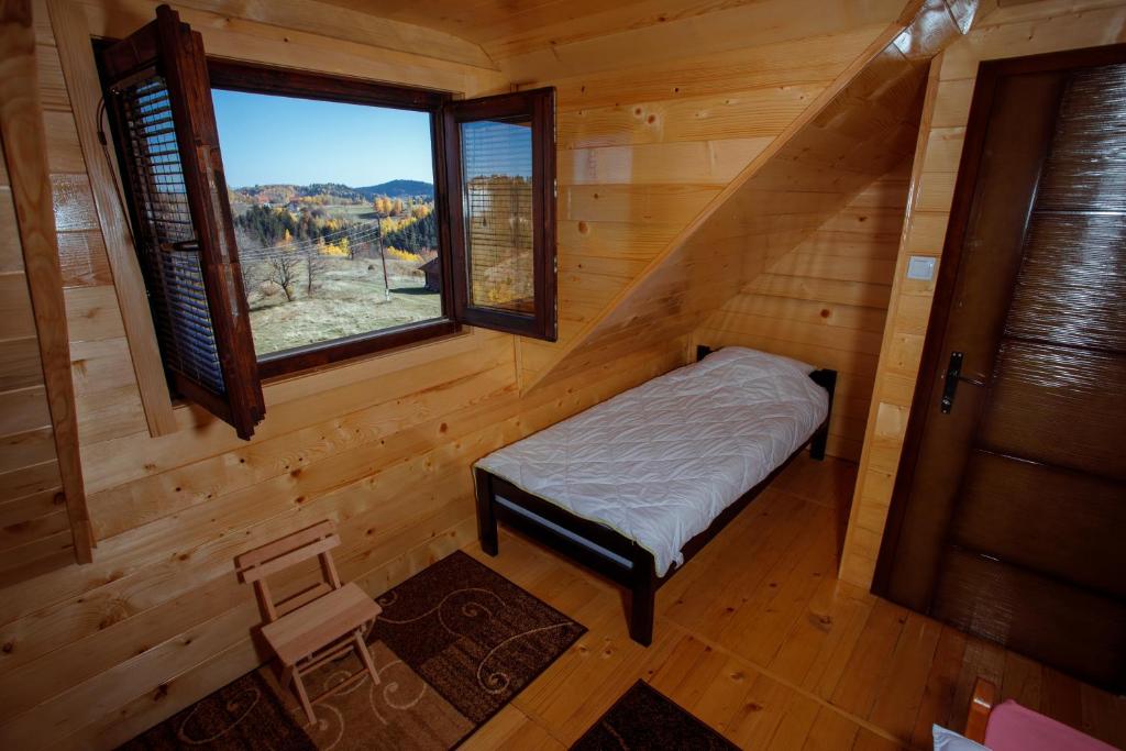 a bedroom in a log cabin with a bed and a window at Seosko turističko domaćinstvo Bojovići (Rajkova koliba) in Nova Varoš