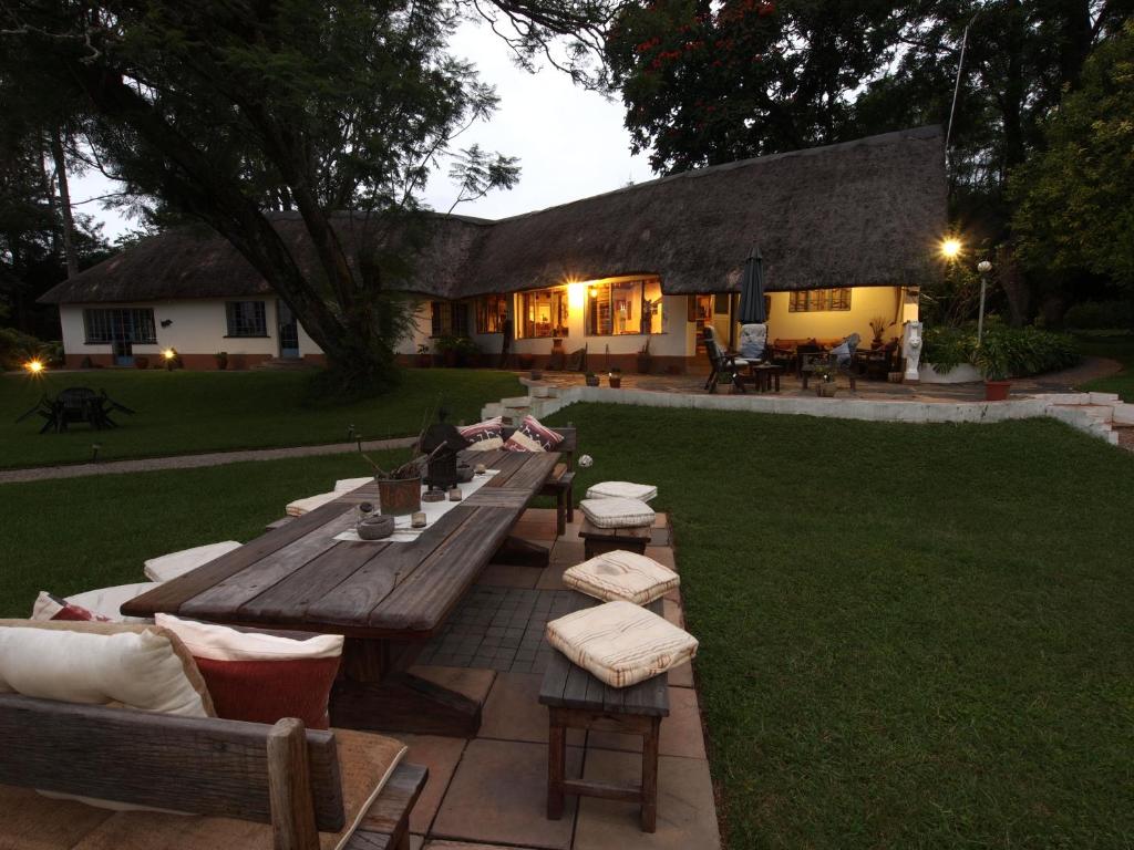 a wooden picnic table and chairs in a yard at Thokozani Lodge in White River