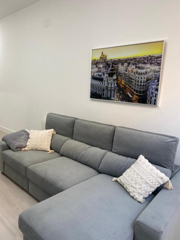 un sofá gris en una sala de estar con una pintura en la pared en Moncloa apartment, con parking en Madrid