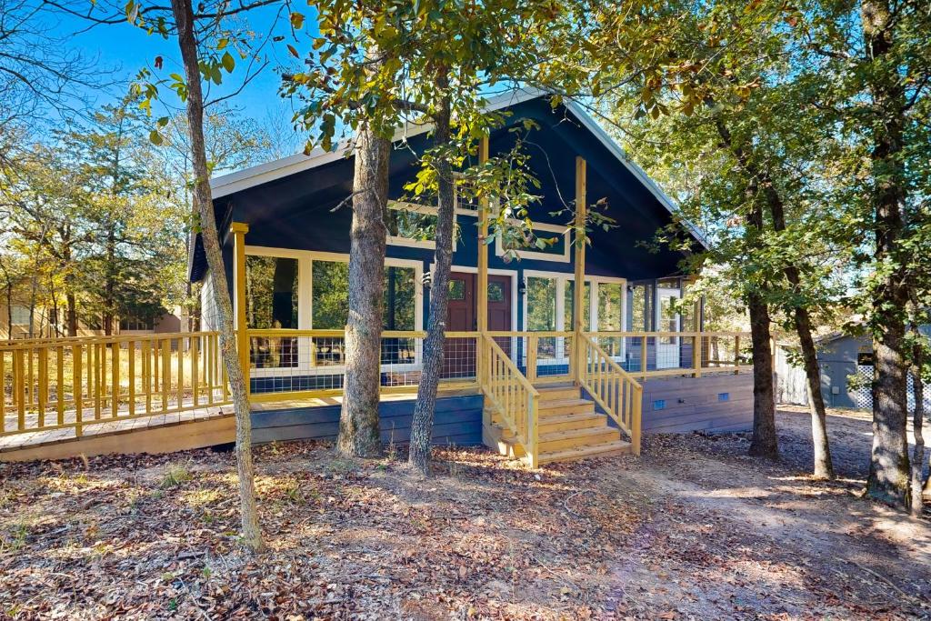 eine Hütte im Wald mit einer Veranda und Bäumen in der Unterkunft Holly Lake Ranch Retreat in Rhonesboro