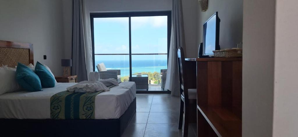 um quarto com uma cama e uma grande janela em Le Marin, Rodrigues Island em Rodrigues Island