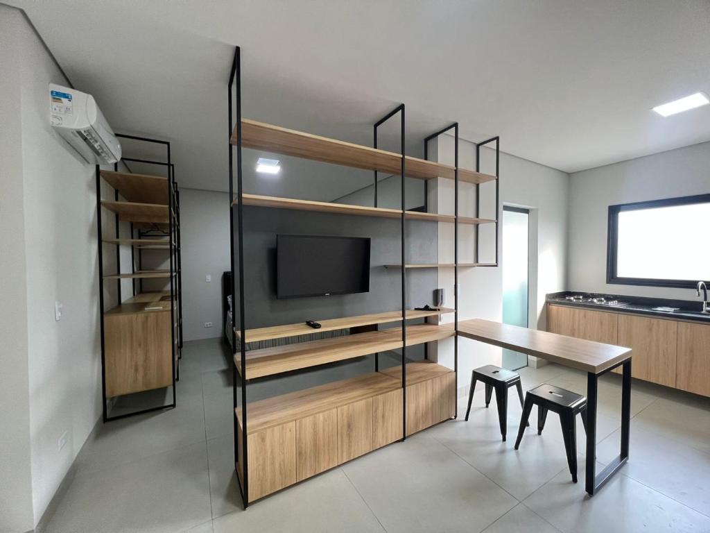 a room with a desk and a tv and a table at SoHo Bosque - Studios & Lofts in Presidente Prudente