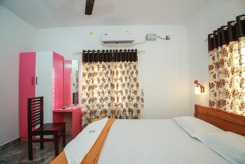 a bedroom with a bed and a chair and curtains at BIJIS HOMESTAY in Alleppey