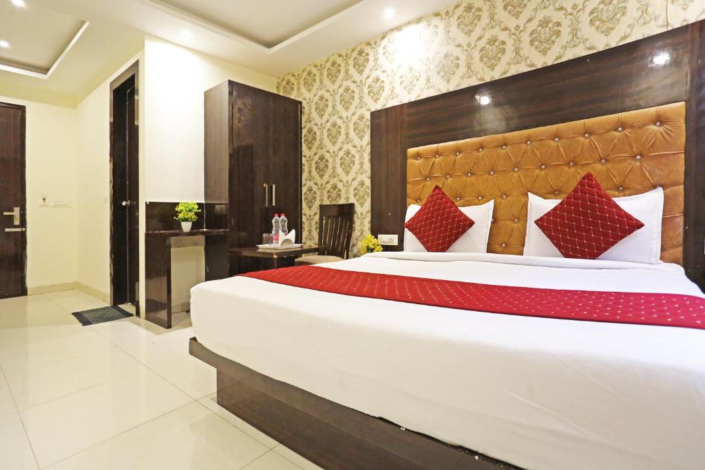ein Schlafzimmer mit einem großen weißen Bett mit roten Kissen in der Unterkunft Iconic Stay Delhi Airport in Neu-Delhi