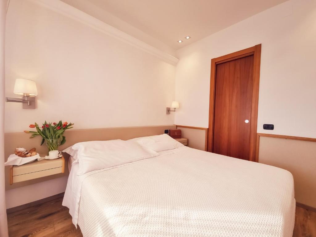 a bedroom with a white bed and a wooden door at Hotel Florida Lerici in Lerici