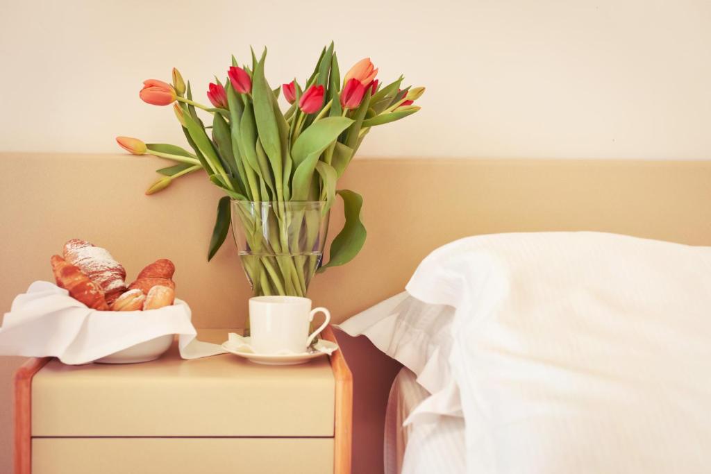 a table with a vase of flowers and a cup of coffee at Hotel Florida Lerici in Lerici