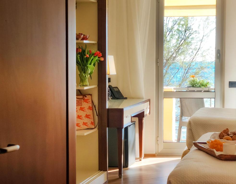a bedroom with a desk and a window with flowers at Hotel Florida Lerici in Lerici