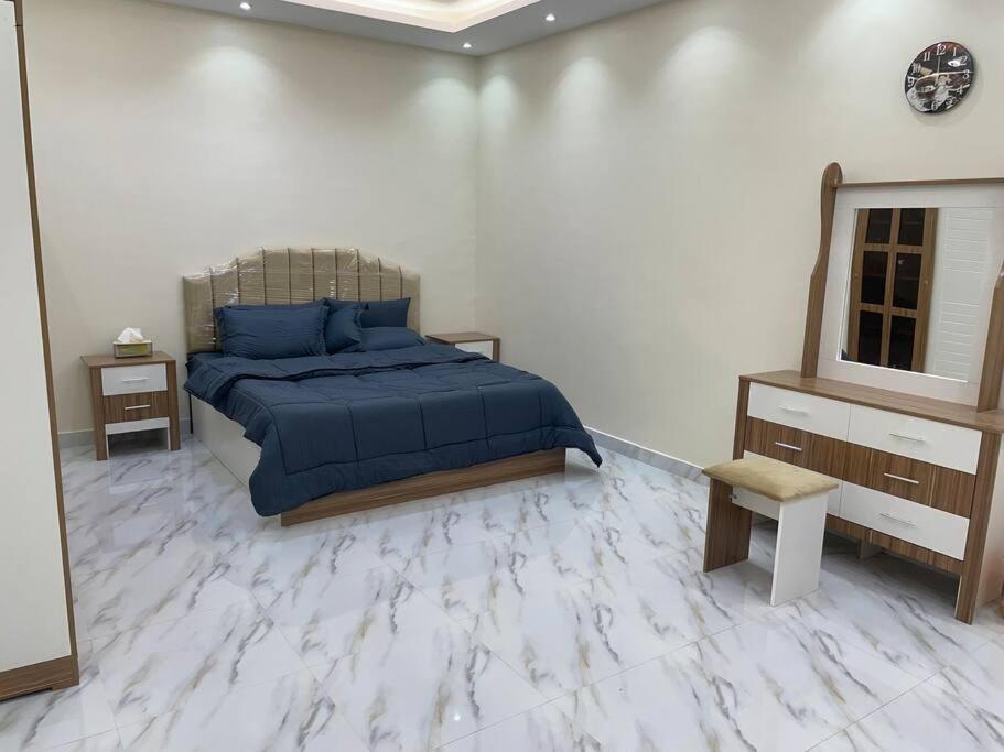 - une chambre dotée d'un lit avec des draps bleus et un miroir dans l'établissement شاليه راقي بمسطحات خضراء وغرفة نوم, à Qufār