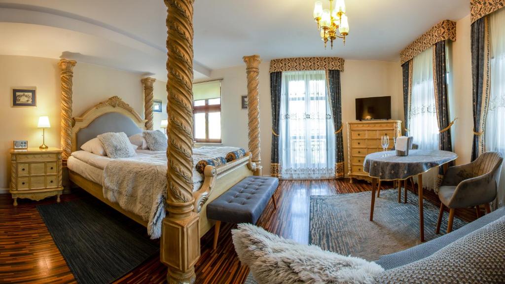 een slaapkamer met een hemelbed en een tafel bij Hotel Maria Helena in Szczawno-Zdrój