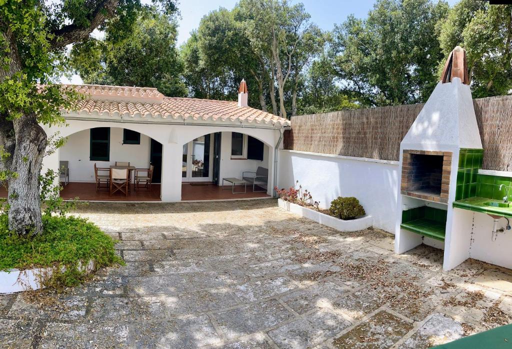 een klein wit huis met een open haard in een tuin bij La maison dans la calanque 1 mn à pied de la plage d'ALCAUFAR 