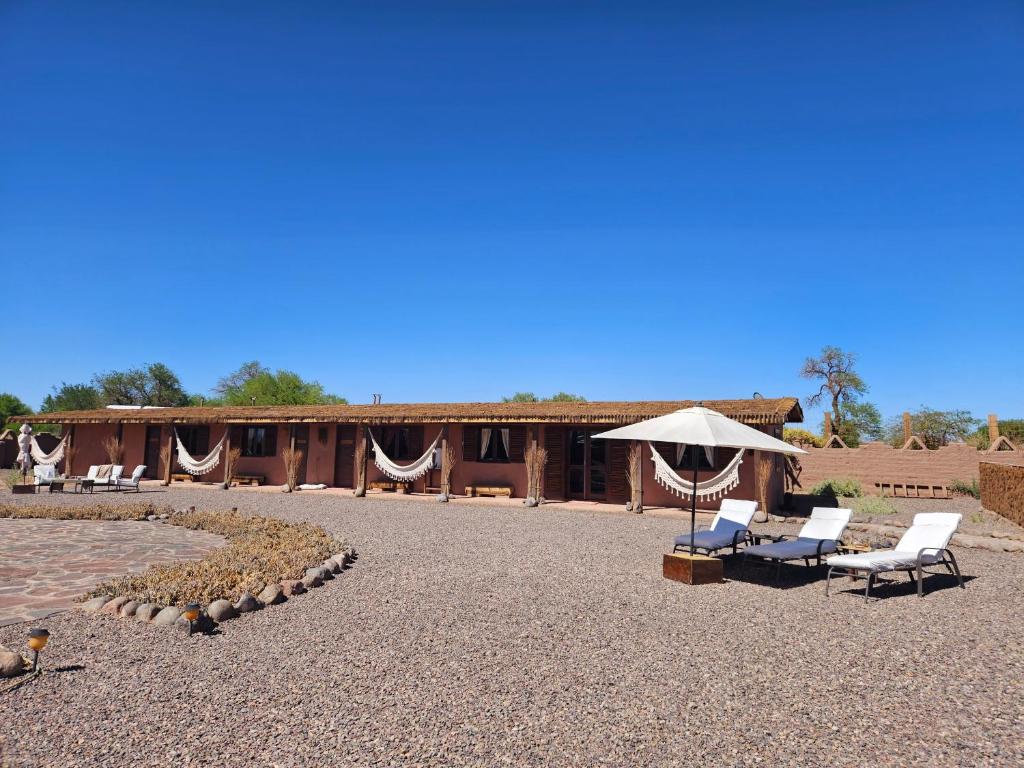 eine Terrasse mit Stühlen, einem Sonnenschirm und einem Gebäude in der Unterkunft Maktub Lodge - San Pedro de Atacama in San Pedro de Atacama