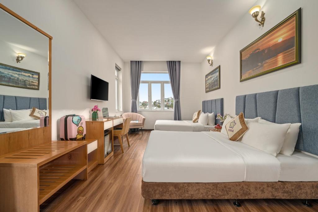 een hotelkamer met twee bedden en een bureau bij Myrtle Boutique Hotel in Da Lat