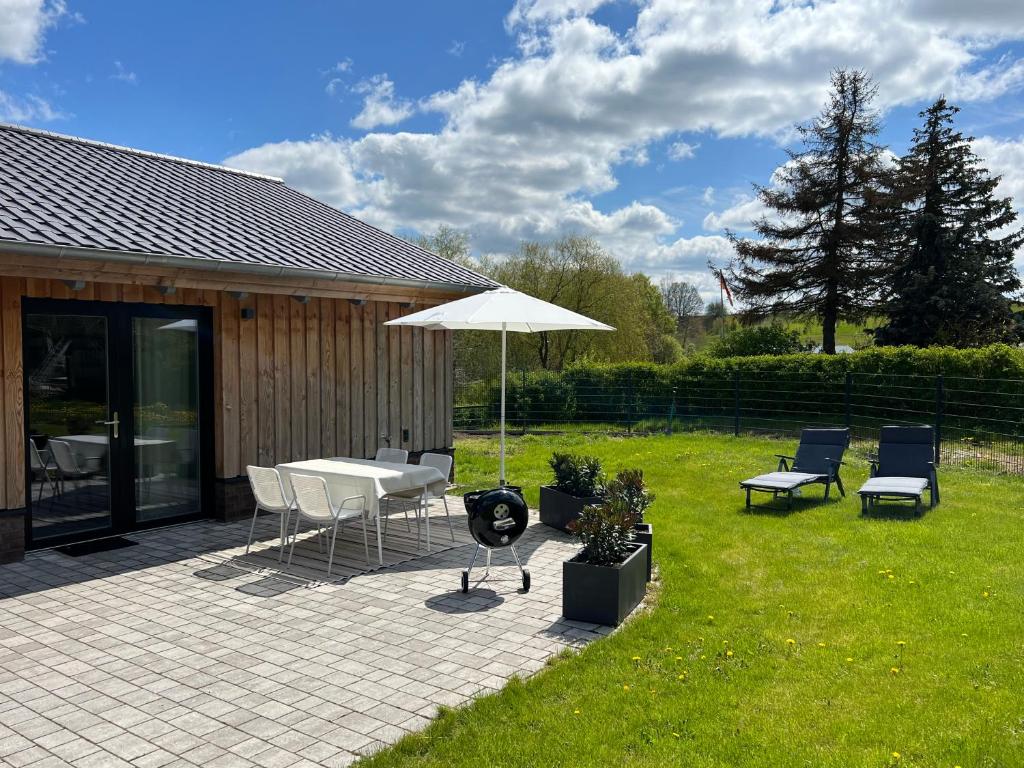 a patio with a table and chairs and an umbrella at Ferienhaus Auszeit mit Sauna in Schwarz