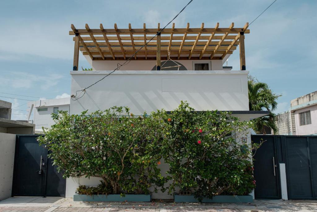 a white house with a bush in front of a fence at Sonsoleá in Luquillo