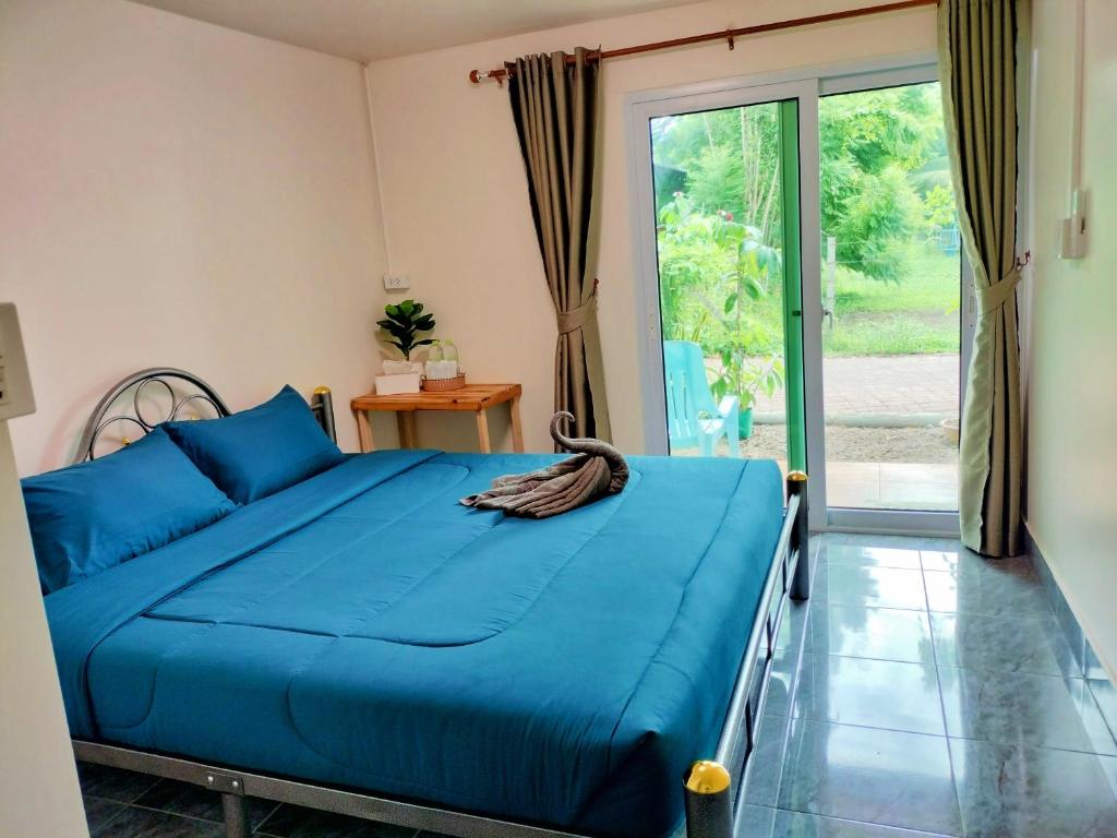 um quarto com uma cama azul e uma porta de vidro deslizante em Kohmook​ Money​ House em Ko Mook