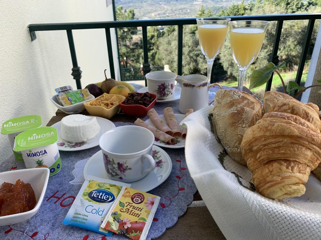 a table with a breakfast of croissants bread and glasses of champagne at Deluxe Studio com terraço e varanda privada - 'Casinha da Amoreira' Guesthouse in Coimbra
