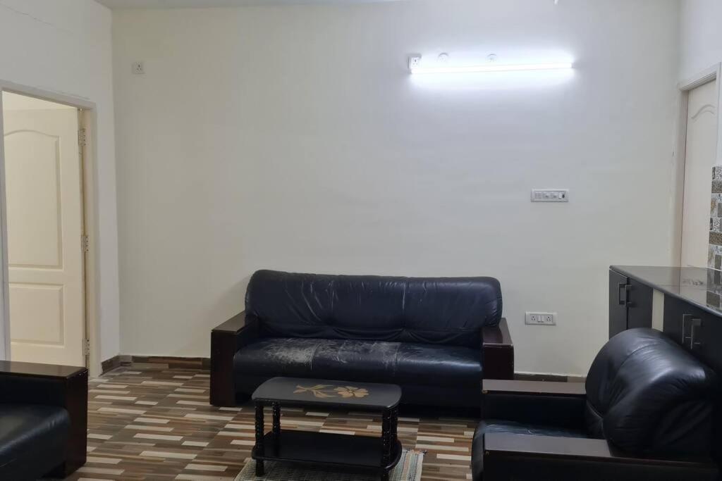 a living room with a leather couch and a table at Kamalam 2 BHK - Non AC in Coimbatore