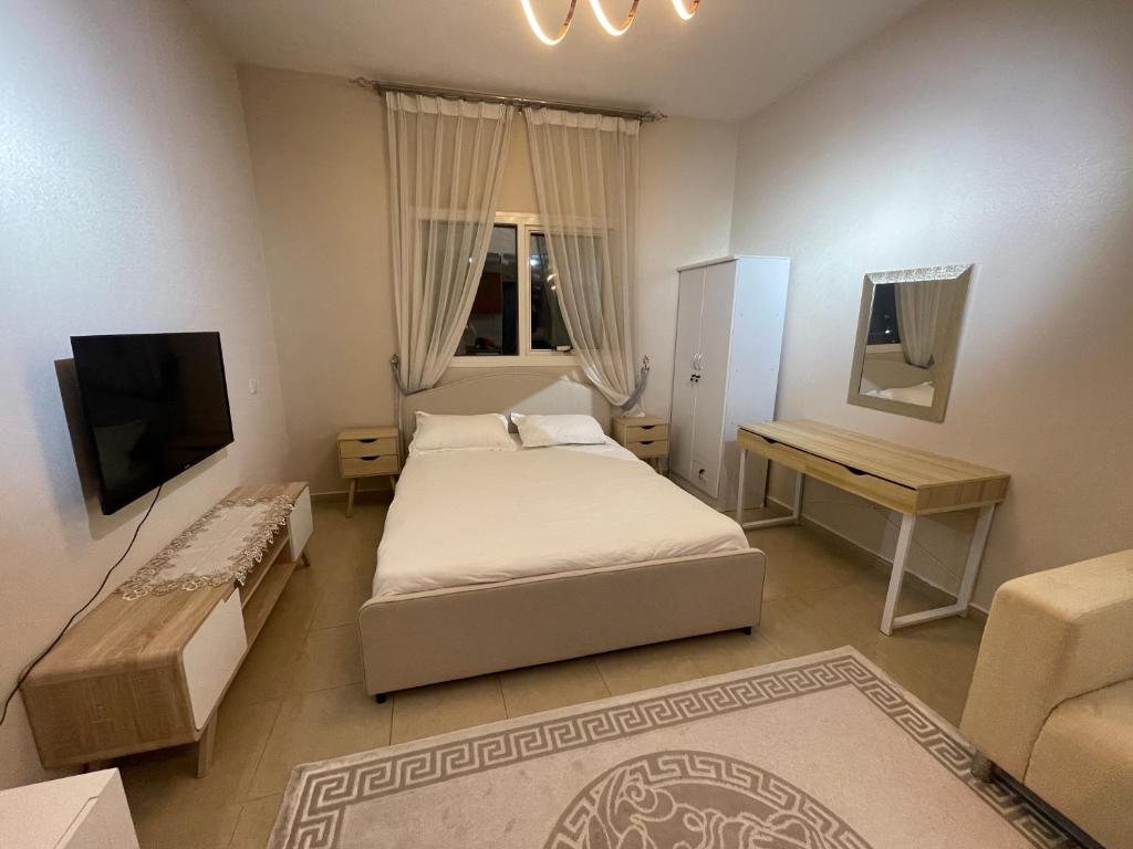 a bedroom with two beds and a desk and a television at Sea view first line Studio Shj in Sharjah