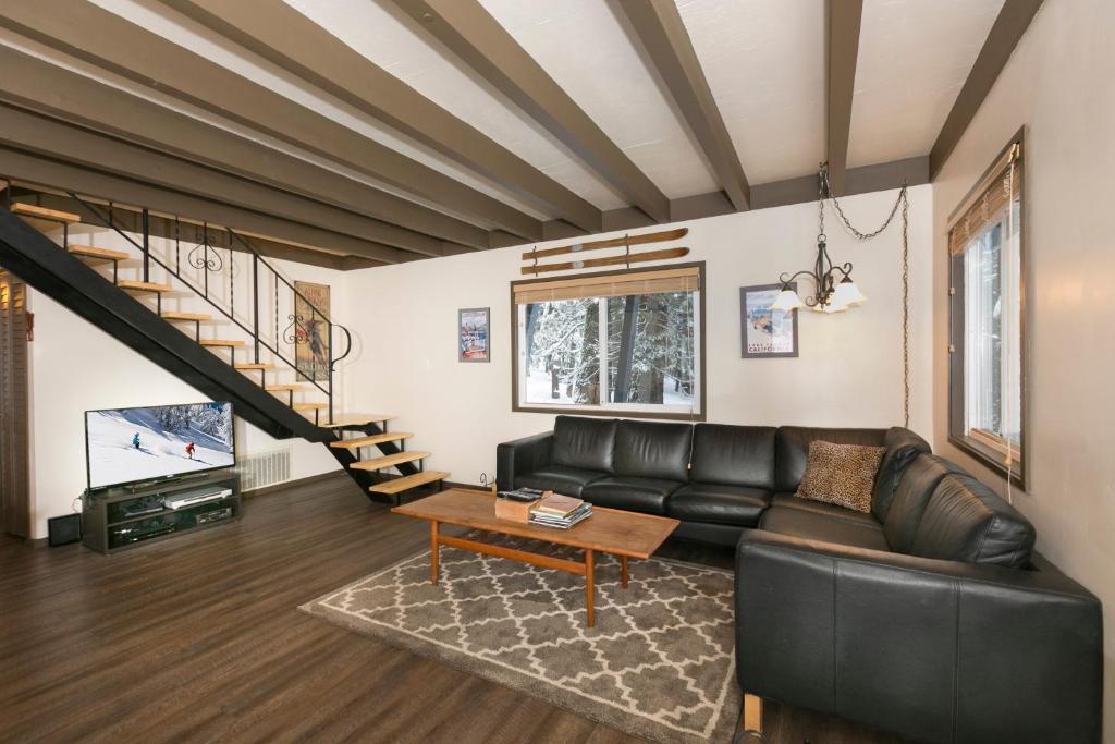 ein Wohnzimmer mit einem Ledersofa und einer Treppe in der Unterkunft Pineland Chalet in Tahoe City - Classic Cabin Wood Fireplace Dog Friendly in Tahoe City